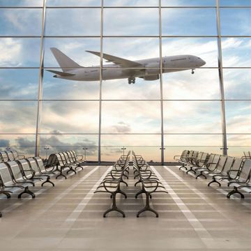An aircraft taking off, seen from an airport departure lounge
