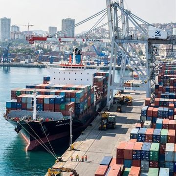 A container ship berthed beside cranes and stacked containers at a port
